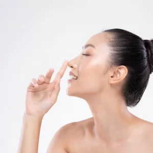 Woman with closed eyes gently touching her nose, representing cosmetic nose surgery.