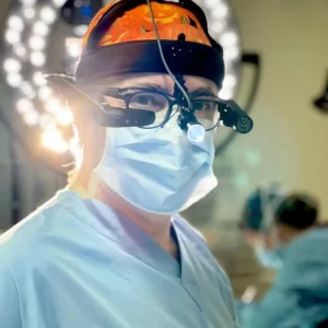Dr. Göksel performing rhinoplasty surgery, wearing surgical loupes and headlight in the operating room.