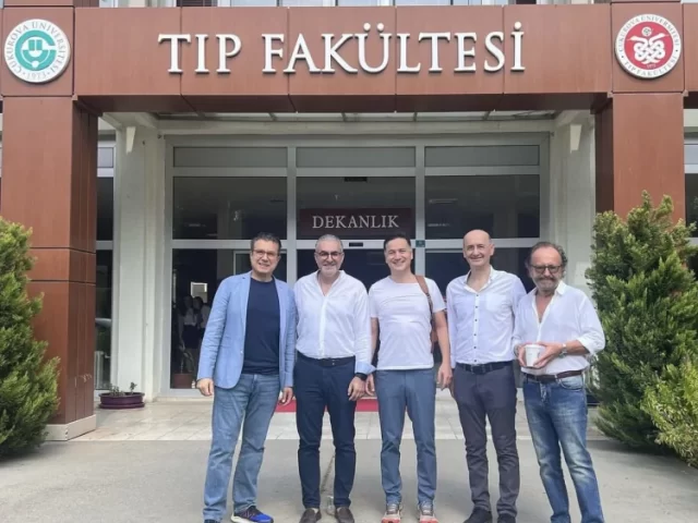 Dr. Göksel standing with fellow physicians in front of a Turkish medical faculty building.